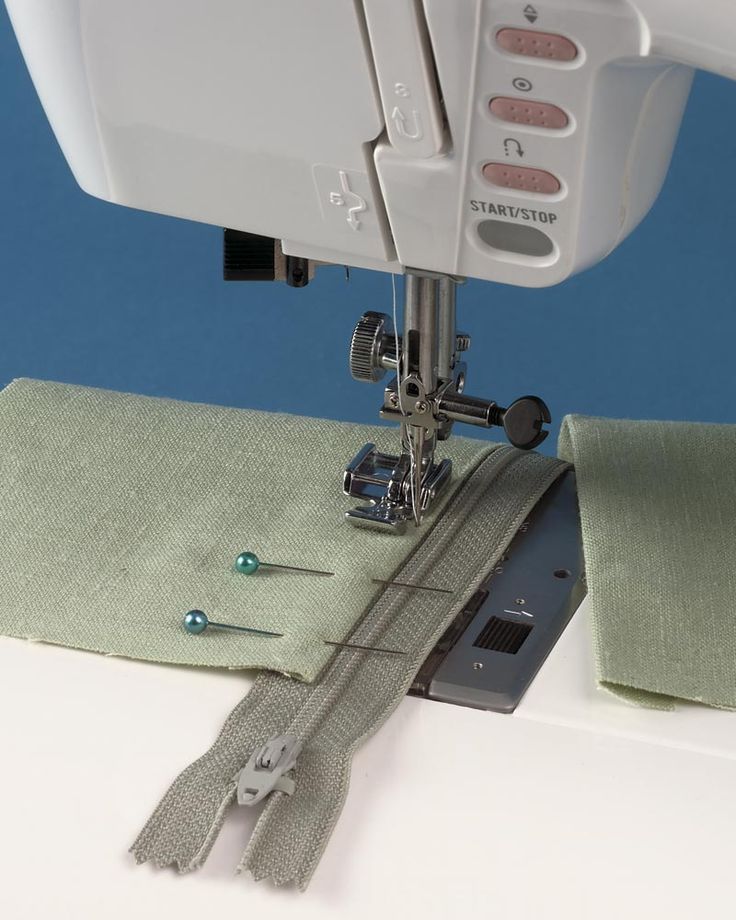 the sewing machine is next to some green cloths and thread on it's side