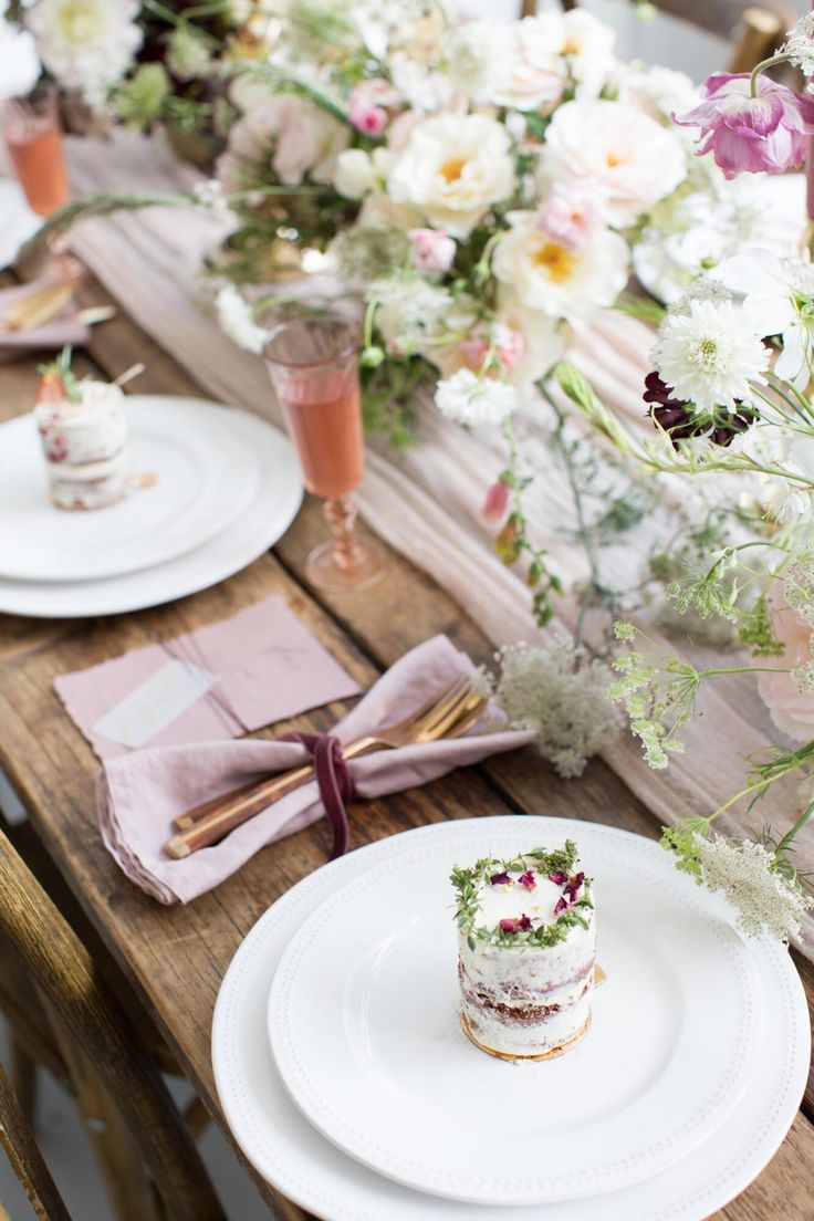 the table is set with flowers and desserts