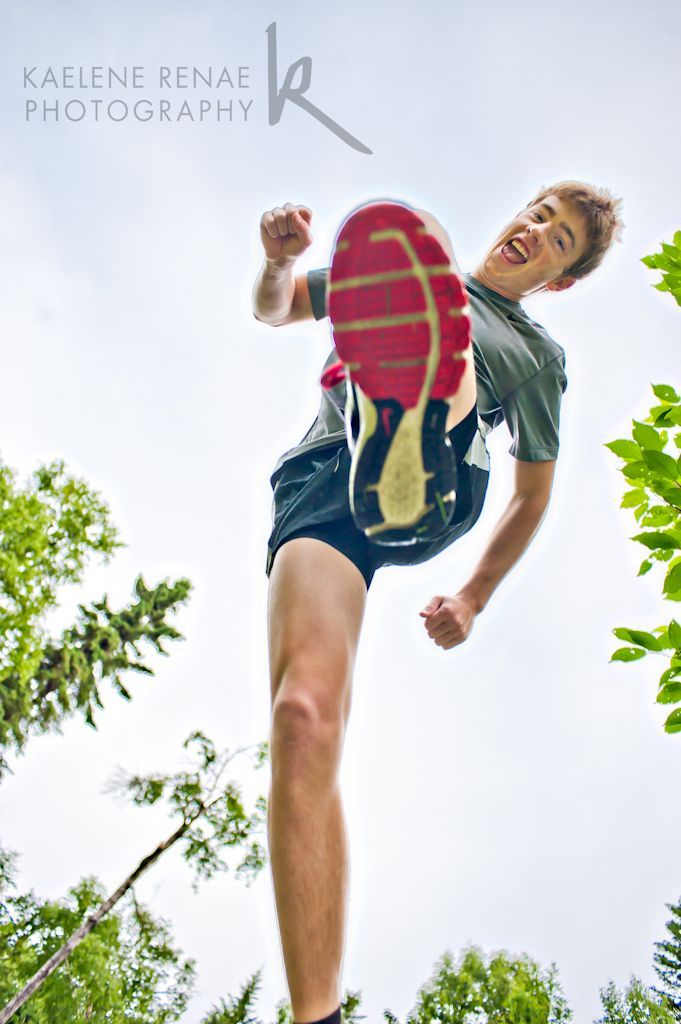 a young man jumping in the air with a frisbee on his feet and wearing blue shorts