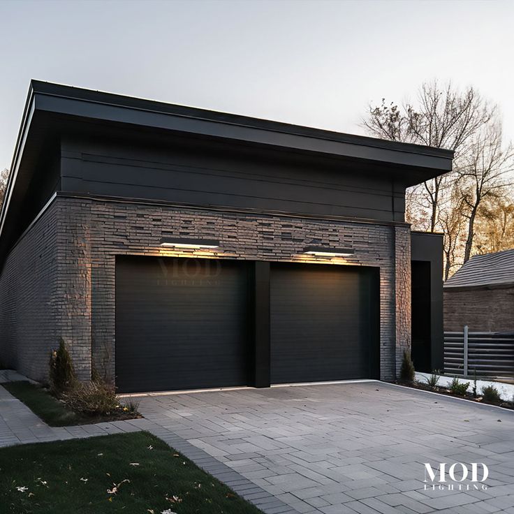 two garages with lights on in front of a brick wall and green grass area