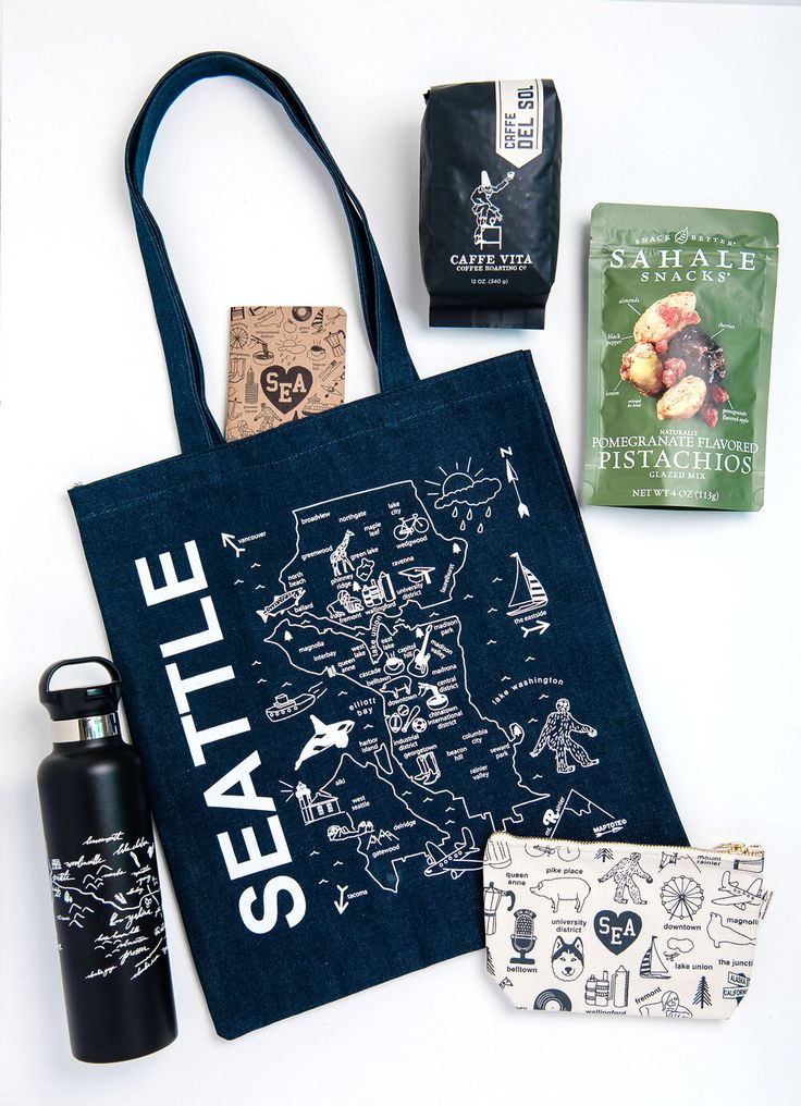 the seattle tote bag is sitting next to other items on display, including a bottle and two tea bags