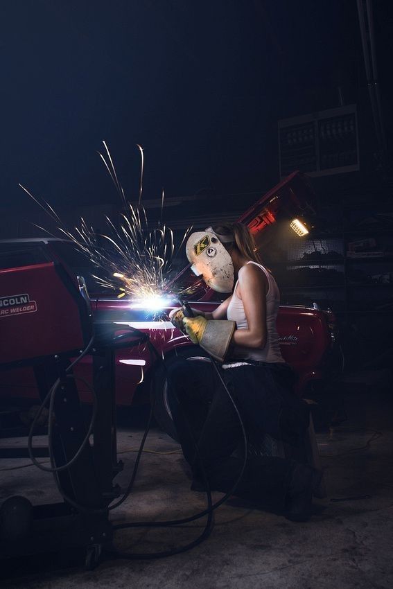 a woman in white shirt working on a machine with sparks coming out of her hands