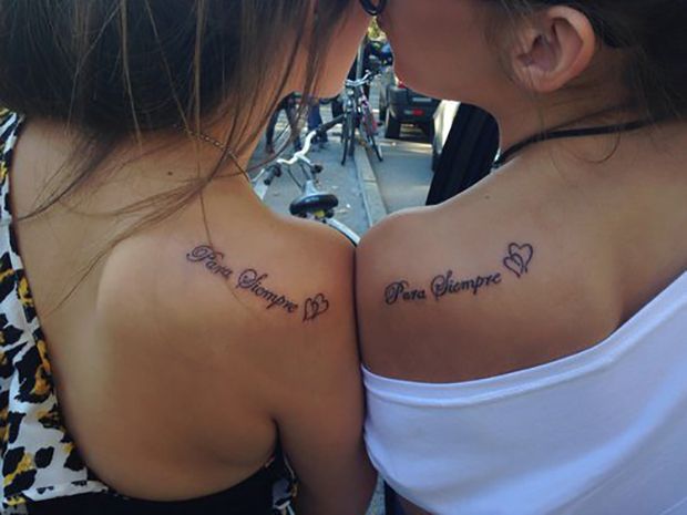 two girls with tattoos on their backs saying love is in the air and one has a heart