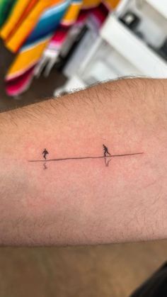 a person with a small tattoo on their arm that has two birds on the line