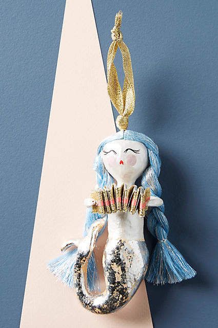 a ceramic mermaid ornament hanging on a wall next to a blue and white triangle