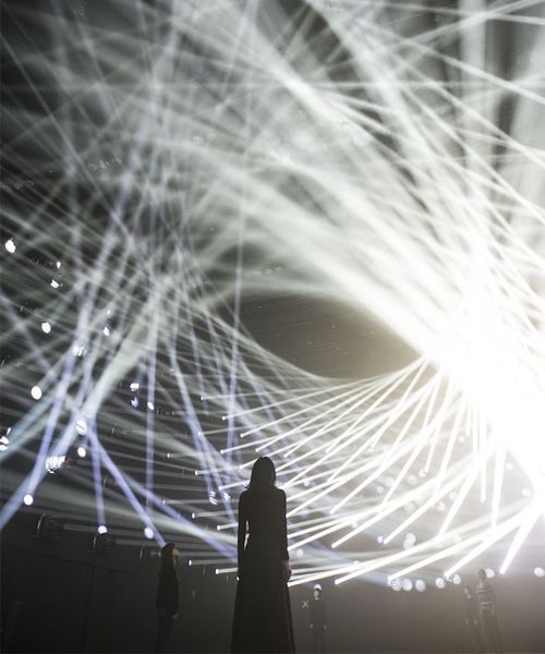 two people are standing in front of a large display of white lights and long lines