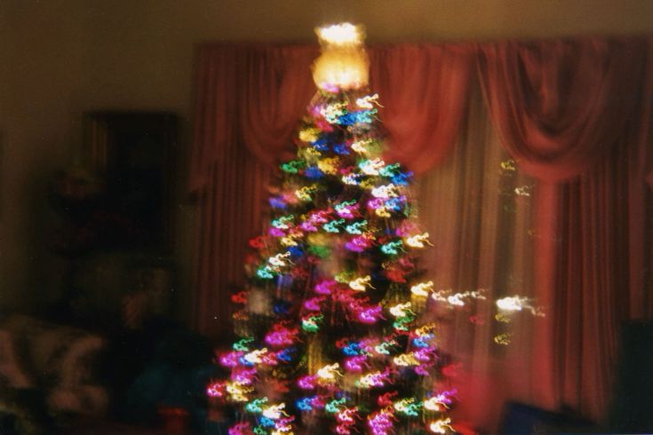 a brightly lit christmas tree in front of a window