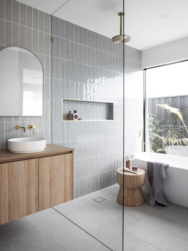 a bathroom with a sink, mirror and bathtub next to a large glass window