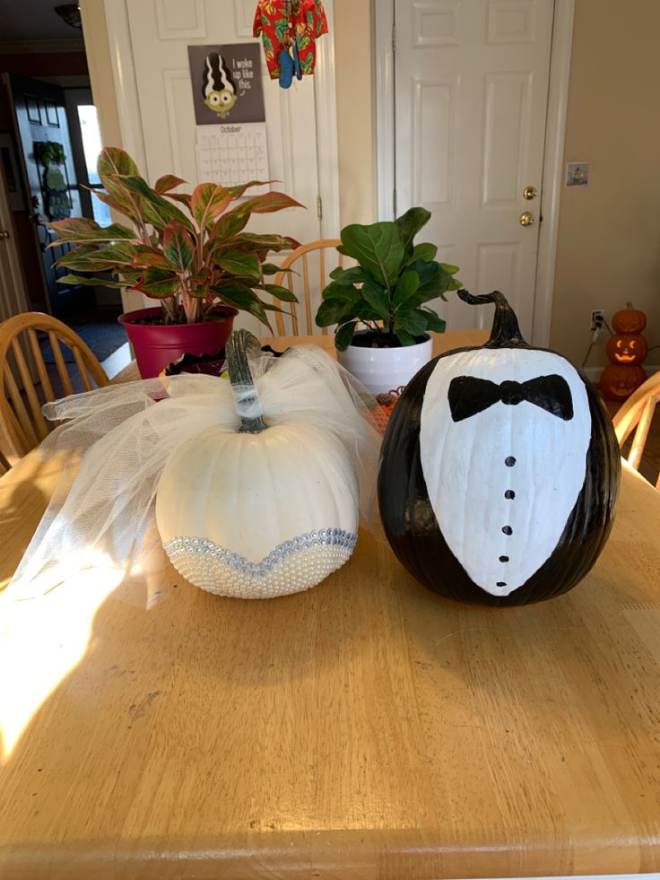 two pumpkins with tuxedo and bow ties sitting on top of a table