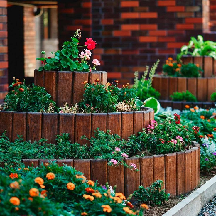 several wooden planters filled with flowers in front of a brick building