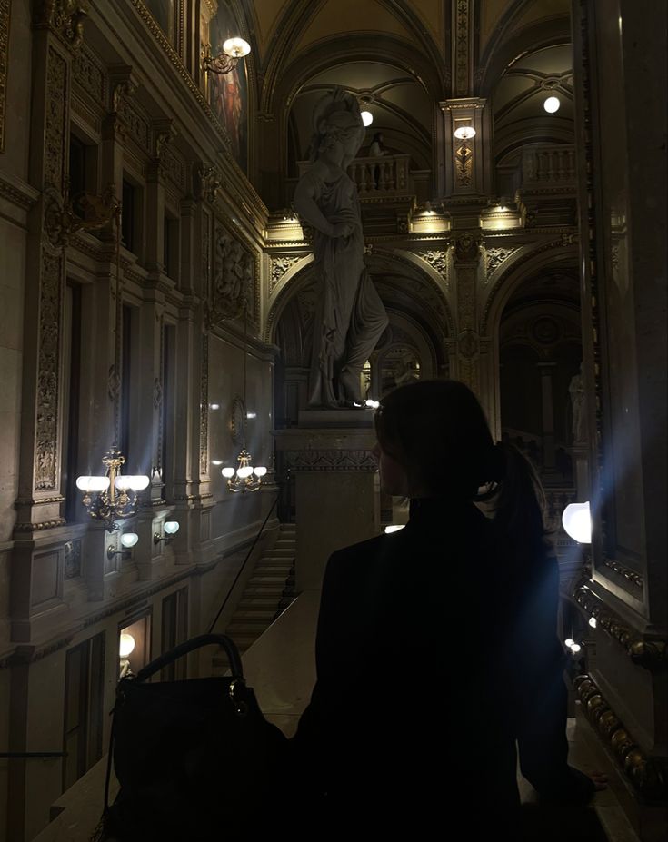 a woman is sitting on the stairs in a building with lights coming from behind her