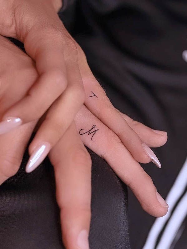 two hands holding each other with tattoos on their fingers and the word love written in cursive writing