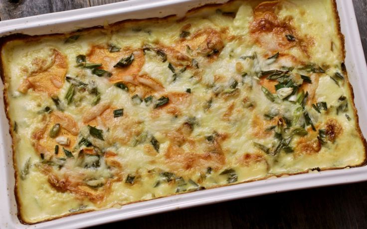 a casserole dish with spinach and cheese in it on a wooden table