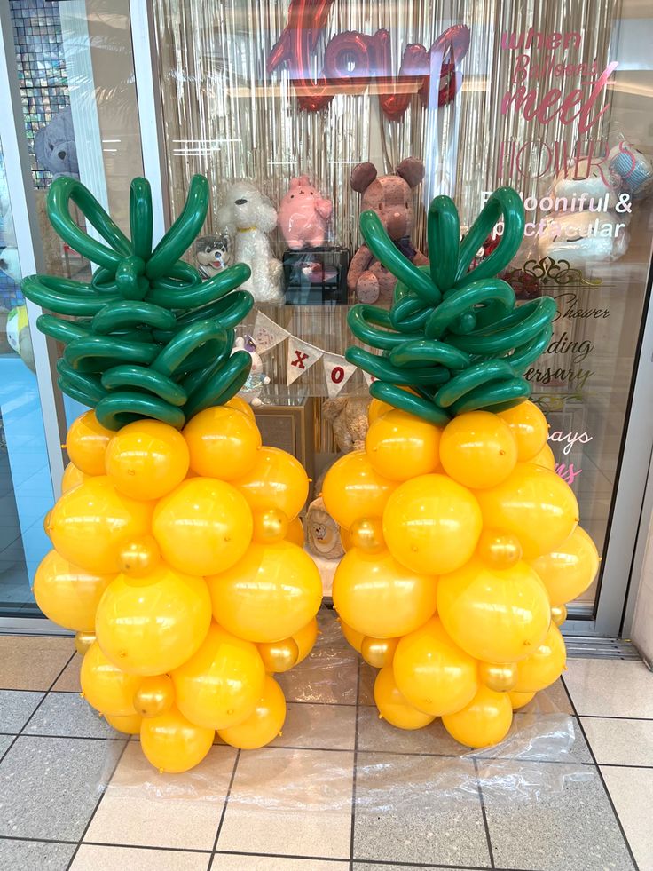 two large yellow balloons shaped like pineapples