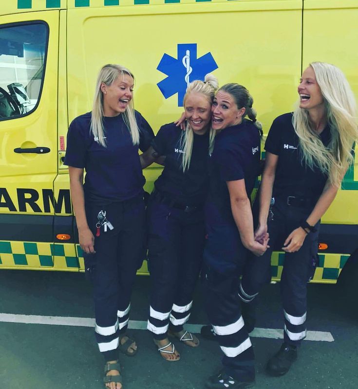 three female paramed staff standing in front of an ambulance truck smiling at the camera