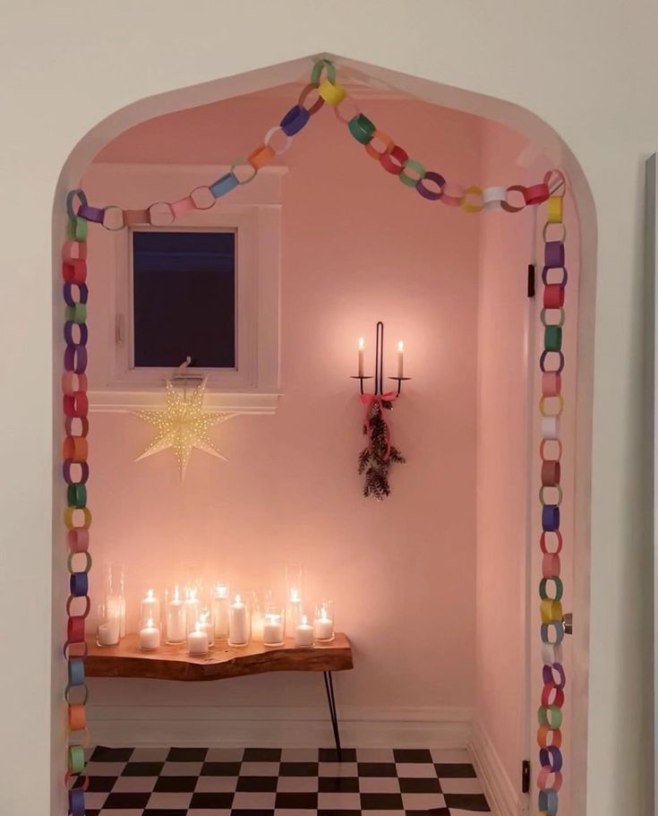 candles are lit in the corner of a room with a checkered floor and pink walls