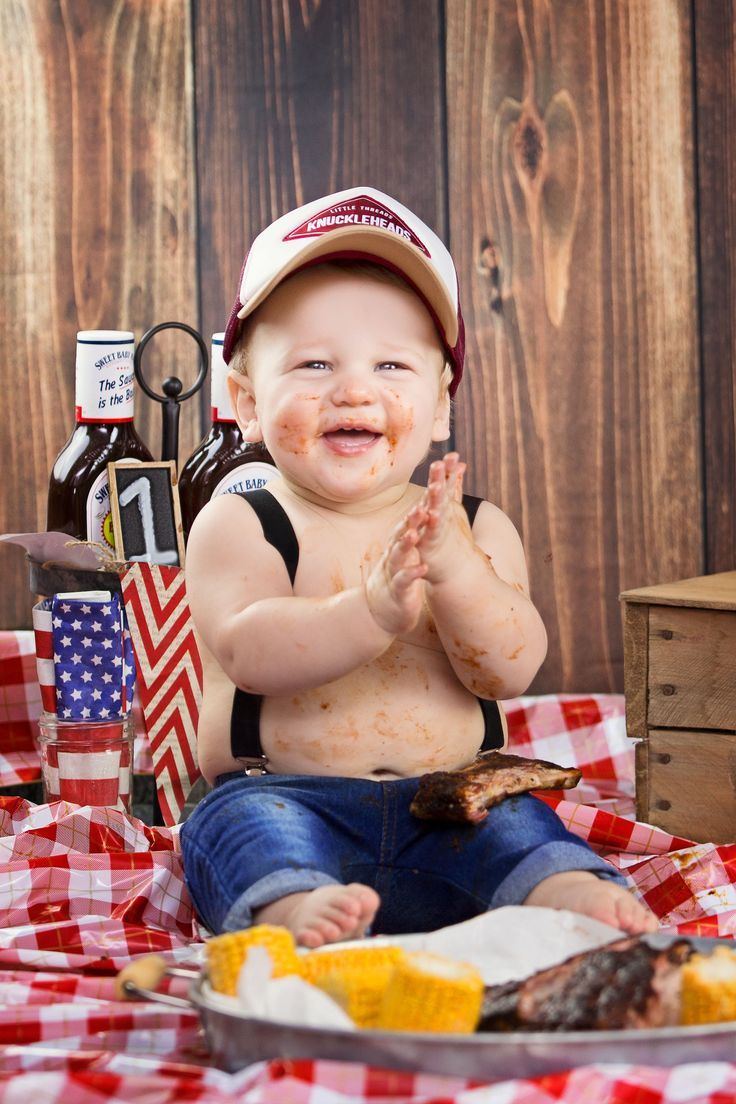 a baby sitting on a table with food in front of him and his hands up