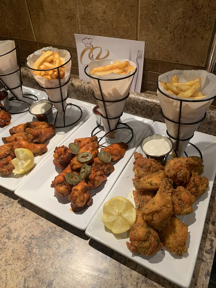 four trays filled with different types of food on top of a marble countertop