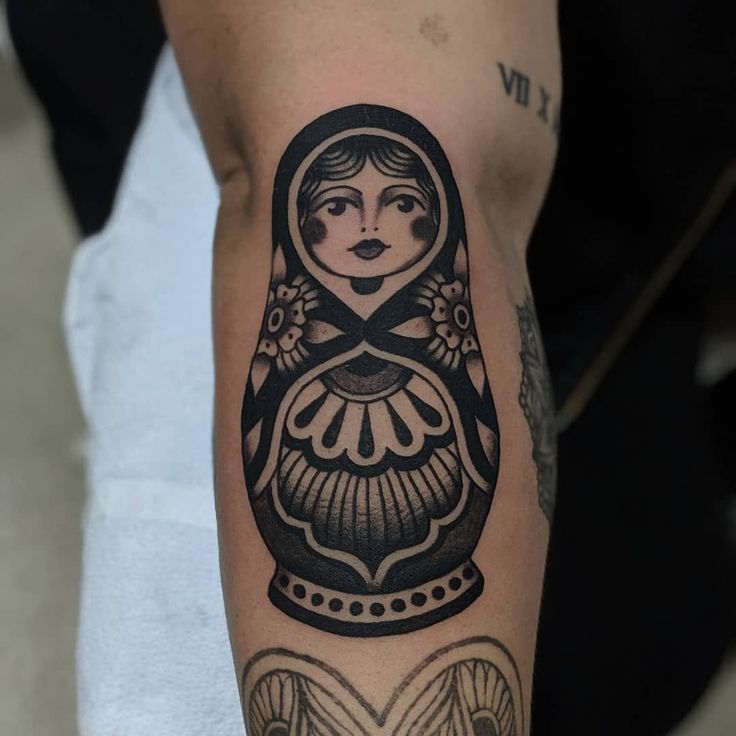 a woman's arm with a black and white tattoo design on the left forearm