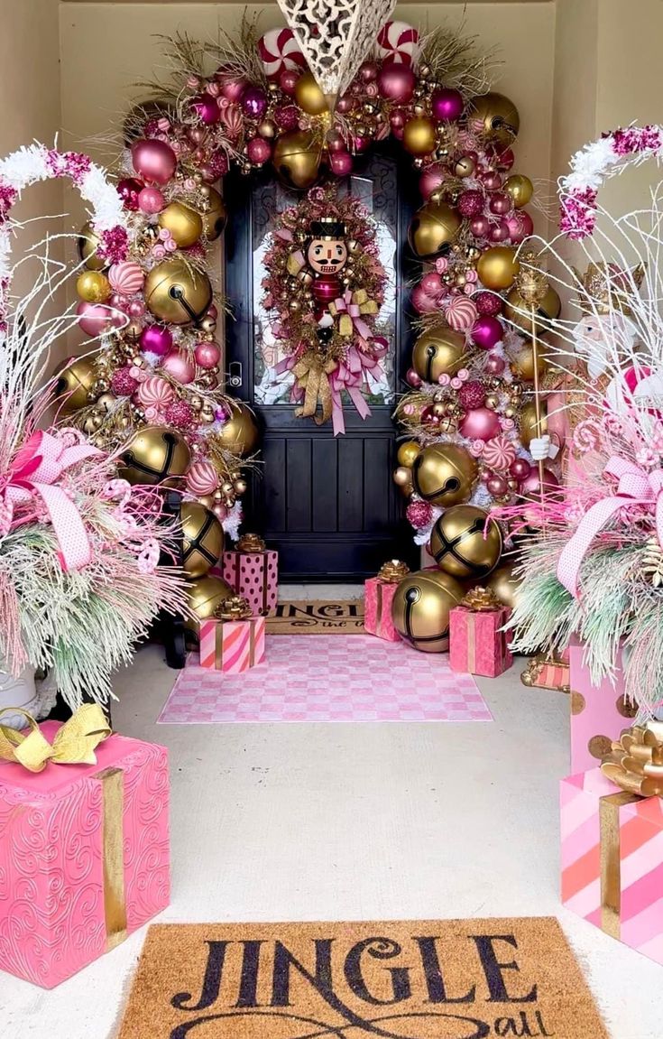 a pink and gold front door decorated for christmas