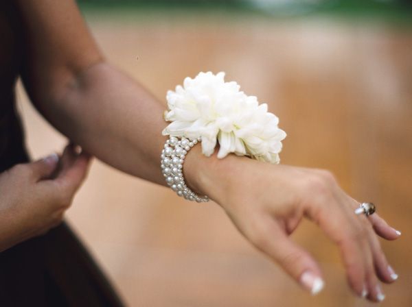 two people holding each other's hand with flowers on it and diamond bracelets