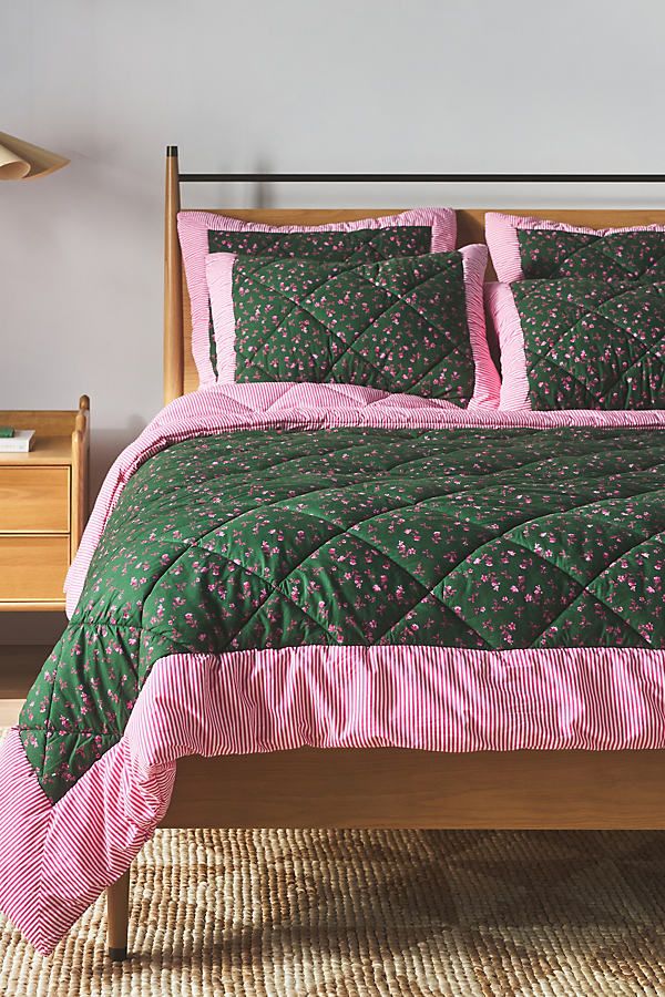 a bed with green and pink bedspread in a bedroom