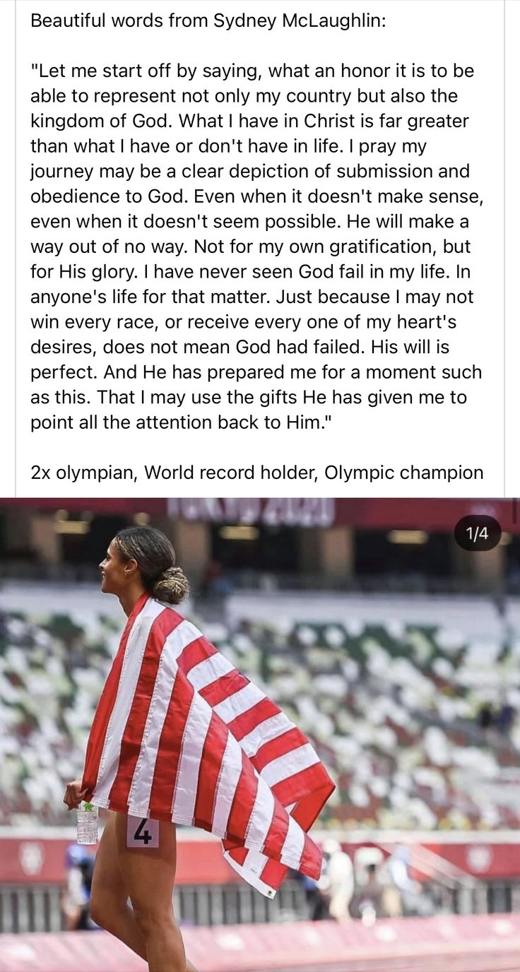 a woman holding an american flag on top of a race track in front of a stadium