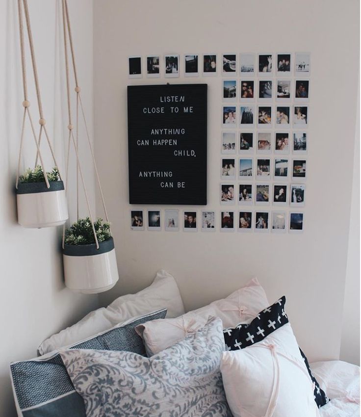 a bed with lots of pillows and pictures on the wall above it, along with hanging planters