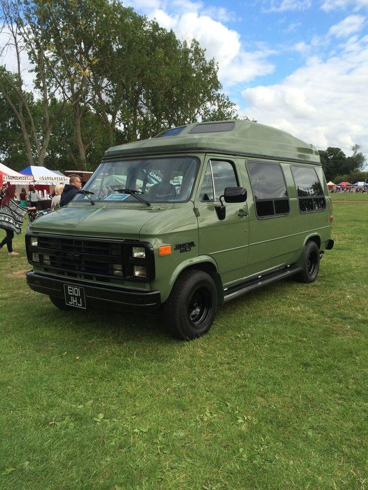 an army green van parked on top of a lush green field