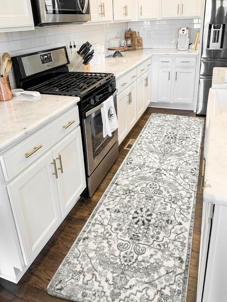 a kitchen with white cabinets and an area rug in front of the stove top oven