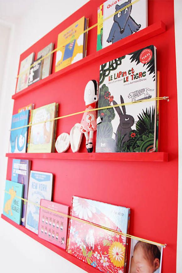 a red book shelf with books on it and an orange string hanging from the top