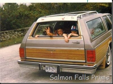 the back of a station wagon with two people sitting in it and one person waving from the passenger seat