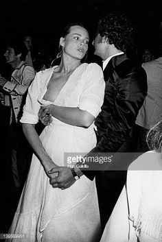 a man and woman dancing together at a party in the evening with other people standing around