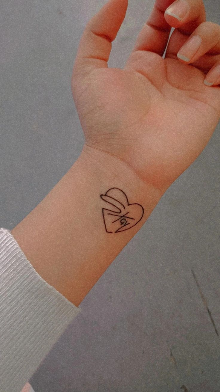 a person's arm with a small heart tattoo on the left side of their wrist