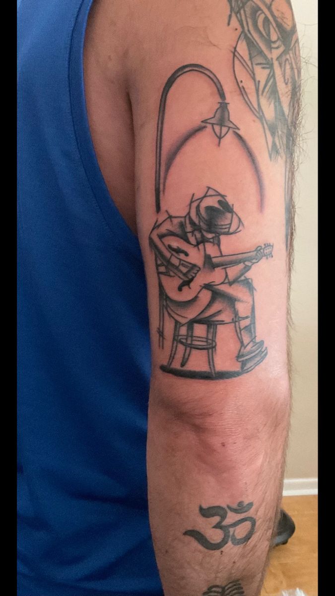 a man with a tattoo on his arm holding a guitar