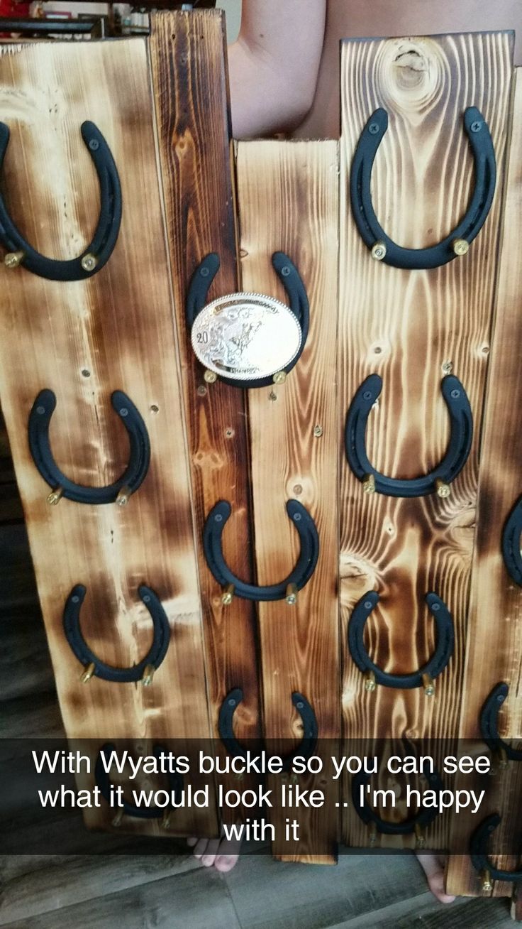 a person standing next to two wooden boards with horseshoes on them and the caption says, with whitis buckles so you can see what it would look like i'm happy with it