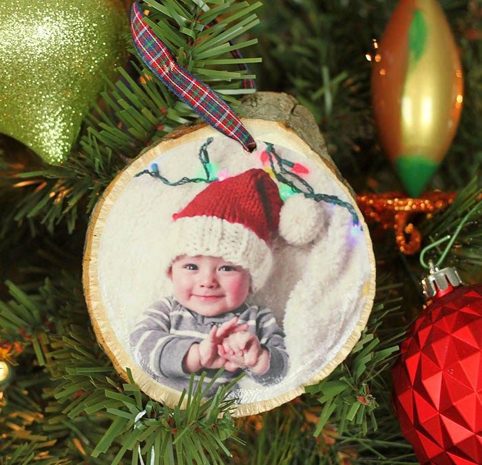 a christmas ornament with a baby's photo on it hanging from a tree