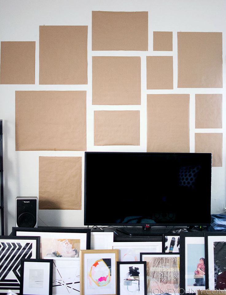 a flat screen tv sitting on top of a wooden table next to a wall covered in pictures