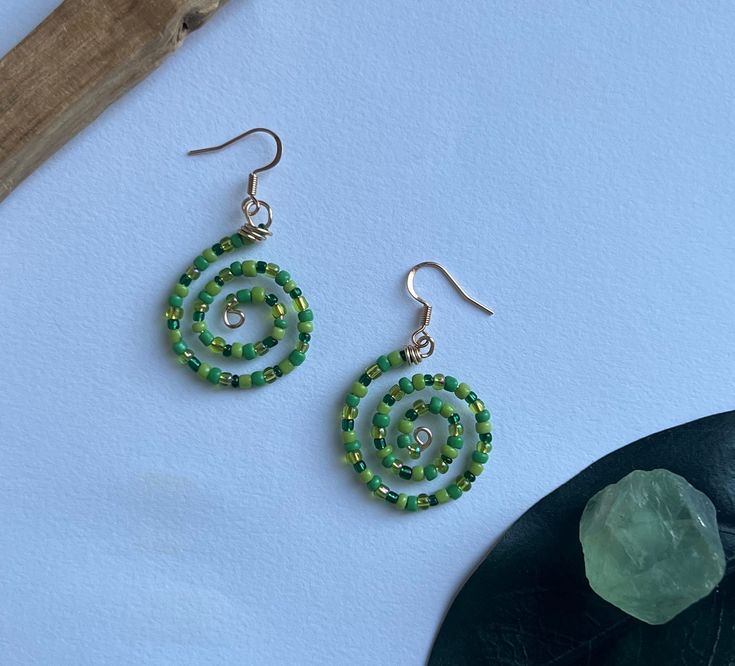 ~These spiral shaped earrings are made with assorted green seed beads. Gold findings and wire used. Earring backs are included. ~Lightweight and fun, these earrings will add flare to any outfit! Green Wire Wrapped Beaded Earrings As Gift, Green Wrap Drop Earrings With Ear Wire, Green Drop Wrap Earrings With Ear Wire, Green Round Beaded Earrings For Gift, Green Spiral Earrings As Gift, Green Wire Wrapped Beaded Earrings For Gift, Green Beaded Fun Earrings, Green Adjustable Wire Wrapped Beaded Earrings, Nickel-free Green Beaded Earrings For Beach