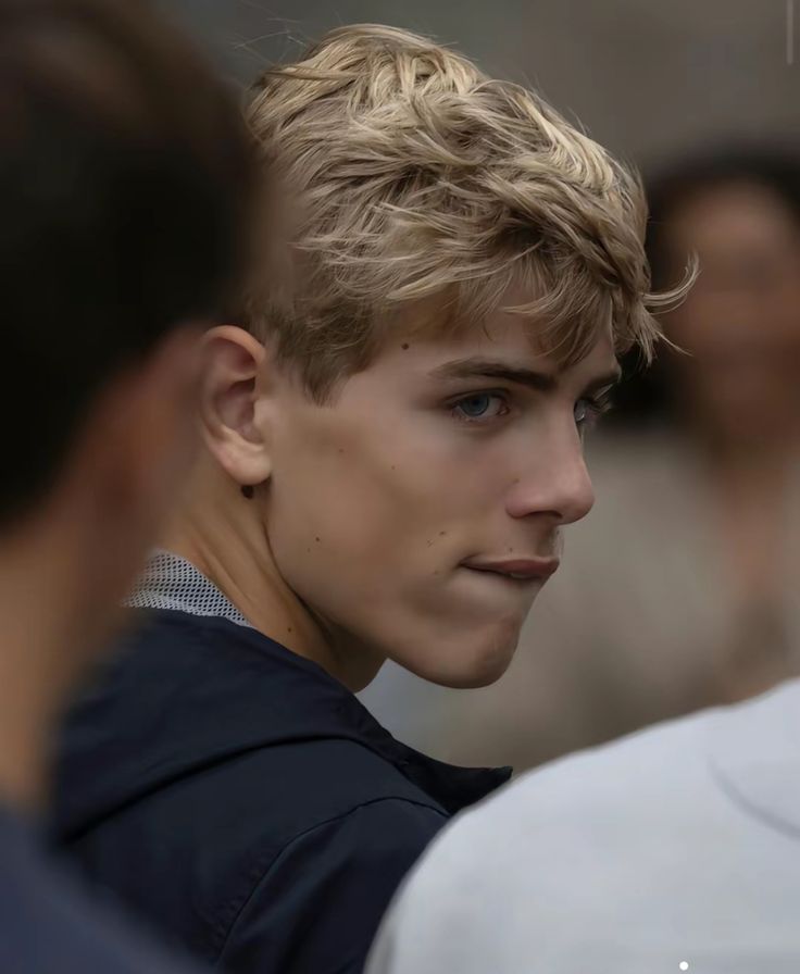 a close up of a person wearing a black shirt and looking at another person in the background