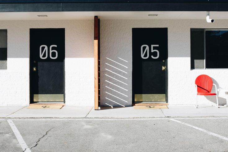 two red chairs sitting in front of black and white door numbers on the side of a building