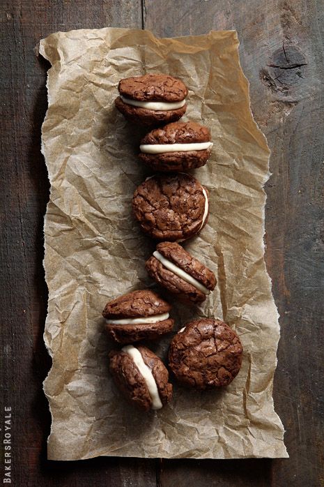 chocolate cookies with white frosting and mini hamburgers on wax paper lined up in a row