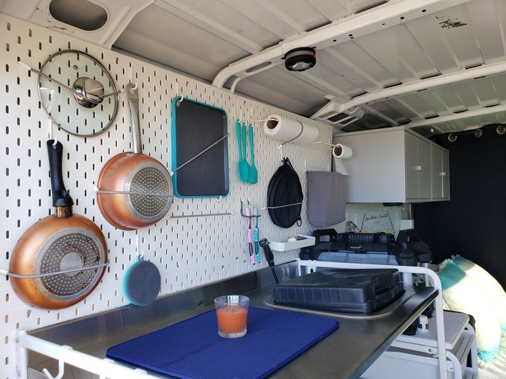 a kitchen with pots and pans hanging on the wall next to a blue mat