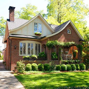 a brick house with white trim and lots of greenery on the front door is shown