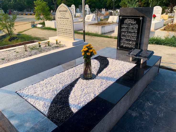 a vase filled with yellow flowers sitting on top of a table next to a grave