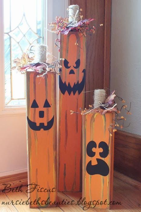 three wooden pumpkins with faces painted on them are sitting in front of a window