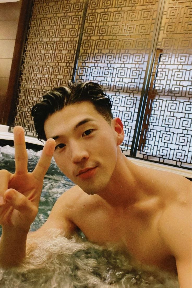 a man in a hot tub making the peace sign