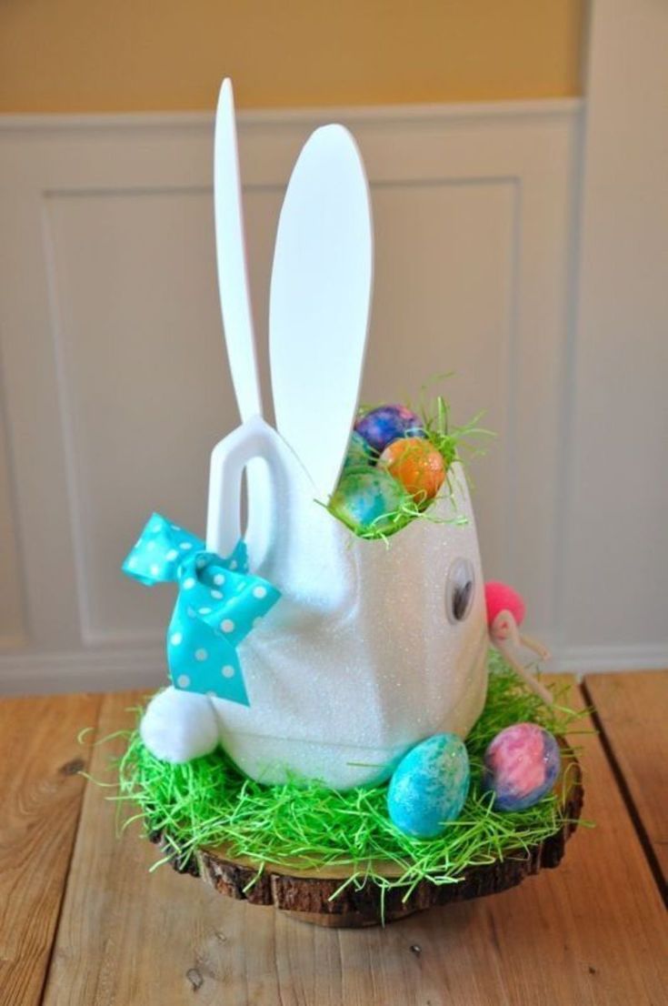 an easter basket with bunny ears and eggs in it on top of a wooden table