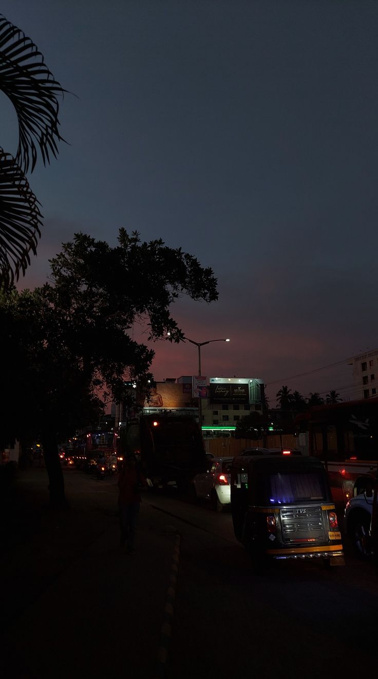 cars are parked on the side of the road at night with buildings in the background