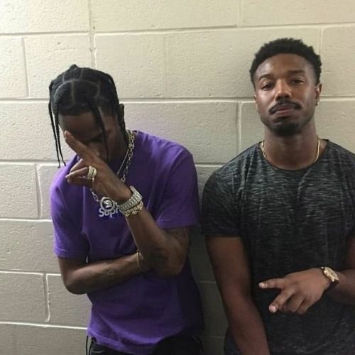 two men standing next to each other in front of a white brick wall with their hands on their face